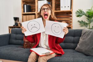 Psicóloga sosteniendo dos folios con un emojis representando emociones