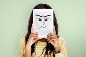 Mujer sosteniendo frente a su cara una careta de enfado